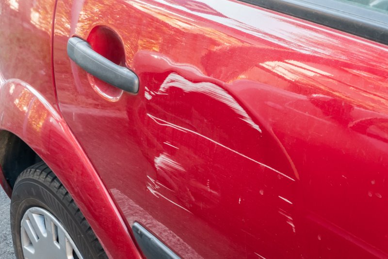Delle in rotem Auto Rotes Auto mit Delle