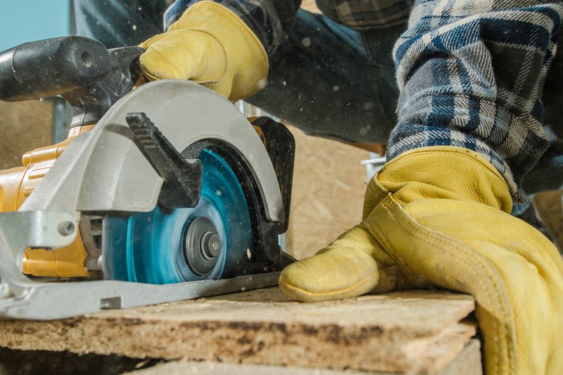 Handkreissäge mit Sicherheitshandschuhen Handkreissäge schneidet Holz