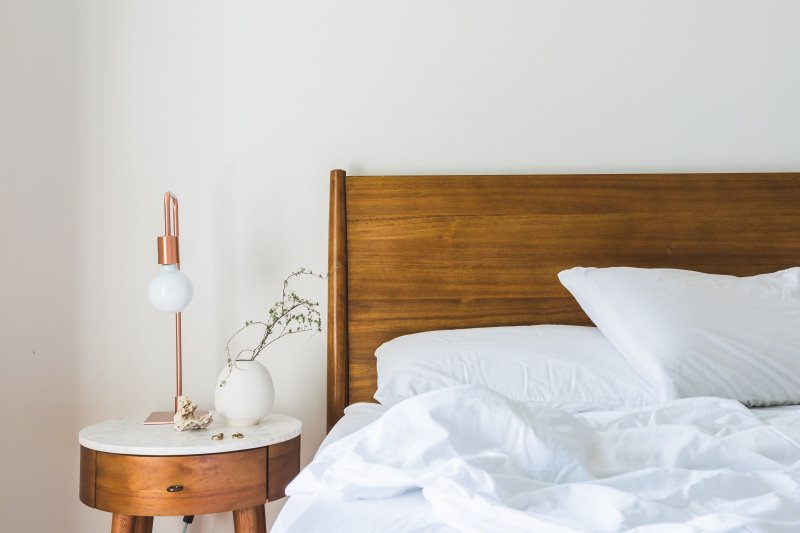 Matratzenauflage im Test Matratzenauflage und Bettwäsche auf einem Bett und Nachttisch