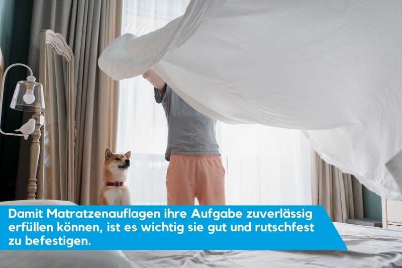 Mann legt Matratzenauflage auf mit seinem Hund